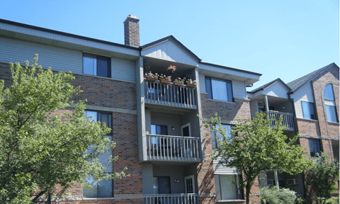A large apartment building with balconies and trees in front.