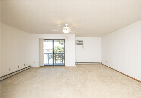 A room with a ceiling fan and a door leading to a balcony.