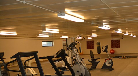 A gym with exercise equipment and a mirror on the wall.