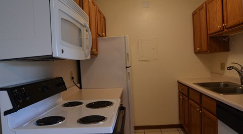 A white stove top oven with four burners and a white microwave above it.