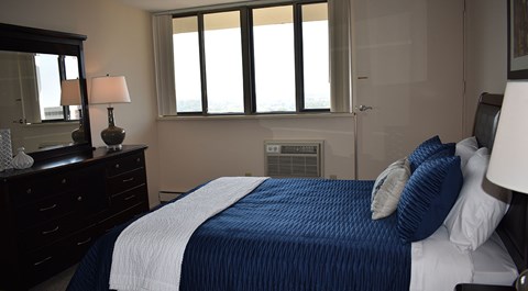A bedroom with a bed, nightstand, and window.