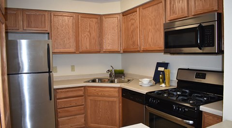 A kitchen with wooden cabinets and a stainless steel refrigerator.