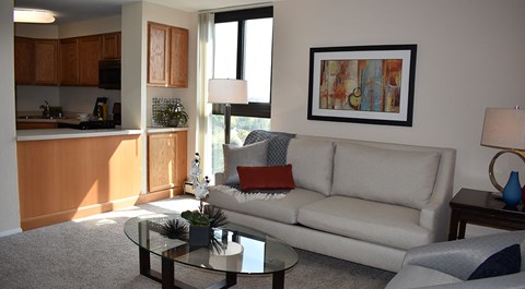 A living room with a couch, coffee table, and a painting on the wall.