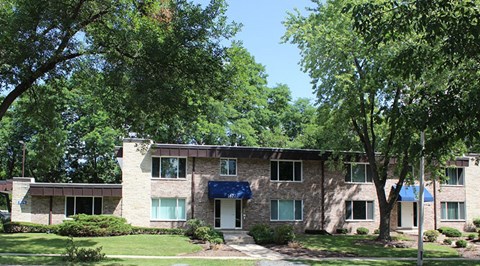 A building with a blue awning is surrounded by trees.