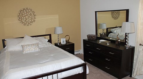 A bedroom with a bed, nightstand, and dresser.