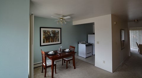 A dining room with a table set for two and a painting on the wall.