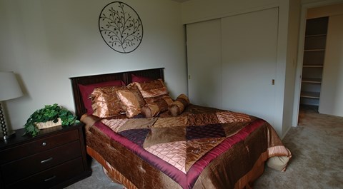 A bedroom with a bed, nightstand, and lamp.