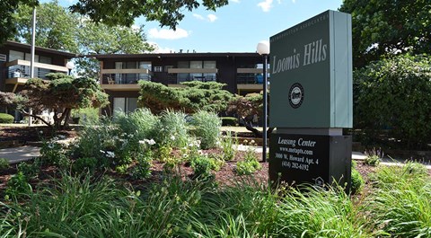A sign for Loomis Hills Leasing Center stands in front of a building.