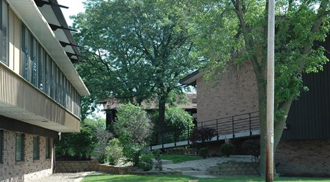 A tree in front of a building with a stone wall.