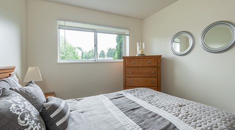 A bedroom with a bed, dresser, and two round mirrors on the wall.