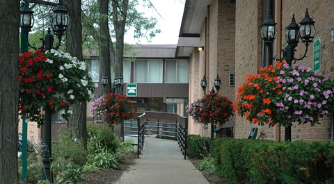 A pathway leads to a building with a green sign in front of it.
