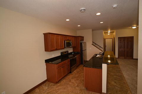 A kitchen with brown cabinets and black countertops.