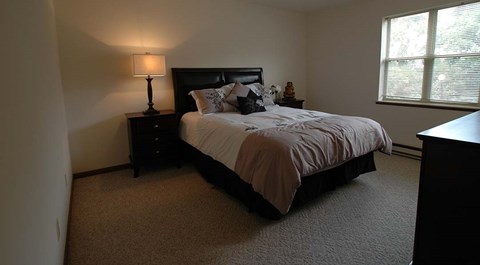A bedroom with a bed, nightstand, and lamp.