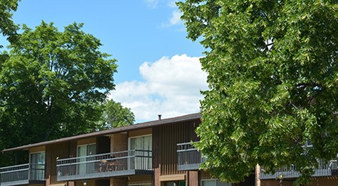 A building with a balcony and trees in front.