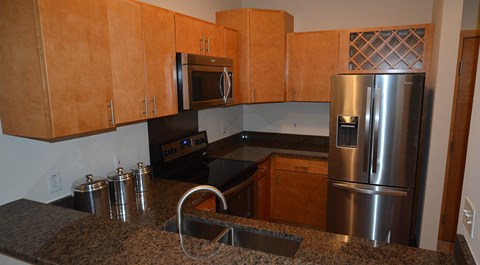 A kitchen with a granite counter top and stainless steel appliances.
