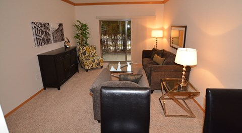 A living room with a black leather chair and a gold side table.