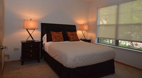 A bedroom with a large bed and two lamps.