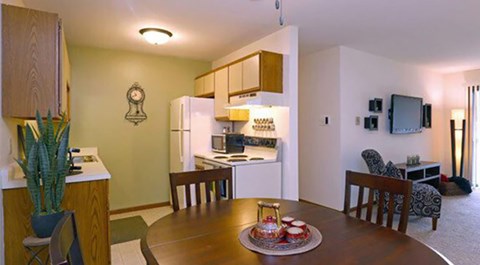 A kitchen area with a table and chairs in the foreground.