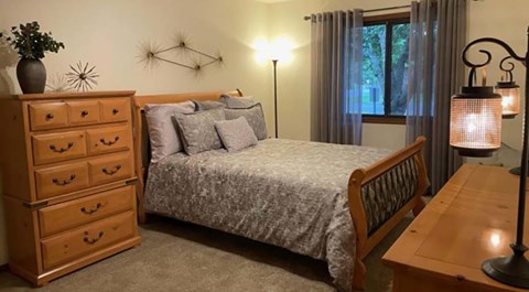 A bedroom with a bed, nightstand, and lamp.