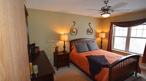 A bedroom with a bed, nightstand, and a ceiling fan.