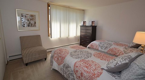 A bedroom with a bed, chair, and a picture on the wall.