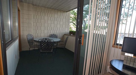 A table with chairs is set up in a room with a glass door.