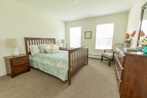 A bedroom with a bed, dresser, and chair.