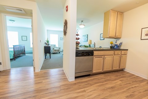 A kitchen with wooden cabinets and a dining area with a table and chairs.