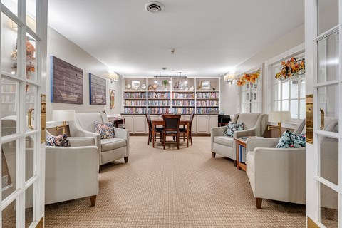 A living room with a carpeted floor and a bookshelf filled with books.