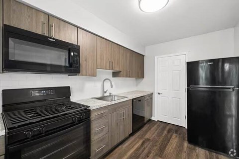 A black stove and microwave in a kitchen with wooden cabinets.