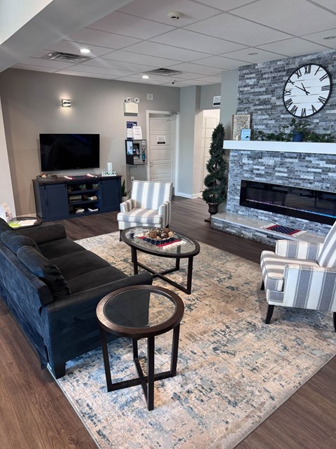 A living room with a fireplace and a large clock on the wall.