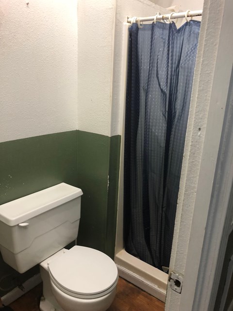 A white toilet in a bathroom with a blue shower curtain.