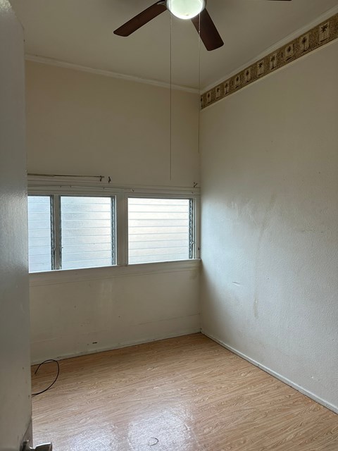 A room with a ceiling fan and a window with blinds.