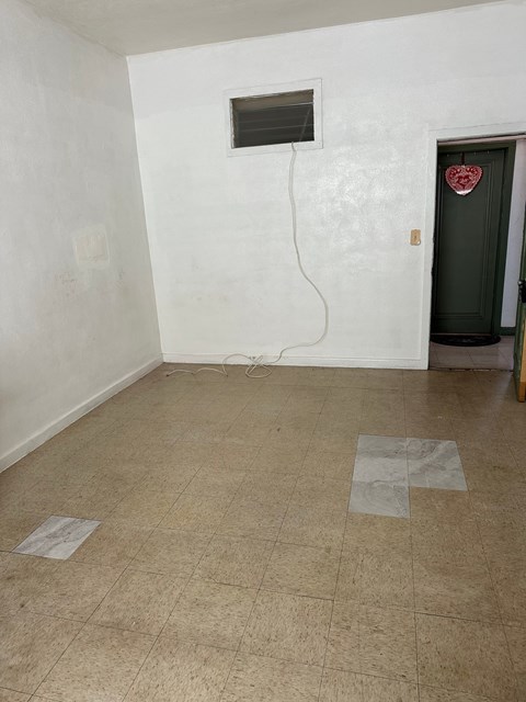 A room with a green door and a white wall with a window.