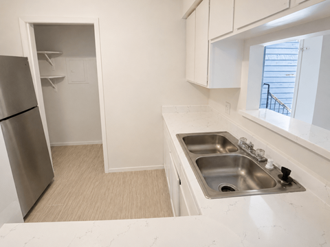 A kitchen with a stainless steel sink and a refrigerator with a door open.