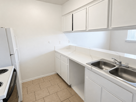 A kitchen with white cabinets and a tiled floor.
