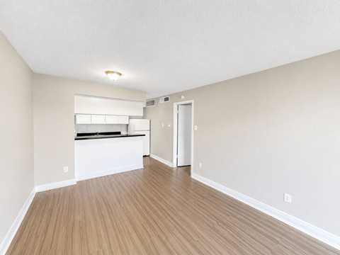 A room with a white ceiling and wooden flooring with a window and a door.