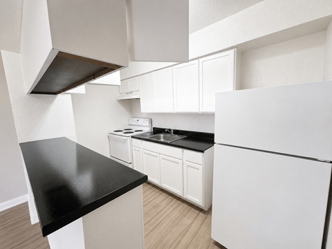A kitchen with white cabinets and a black countertop.