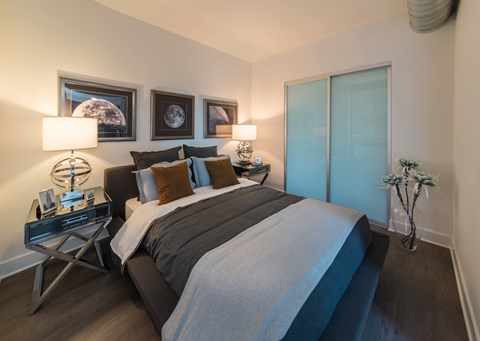 A bedroom with a bed, two lamps, and a vase with flowers.