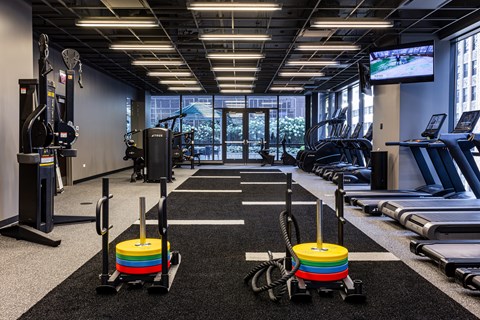 A gym with a row of treadmills and elliptical machines.