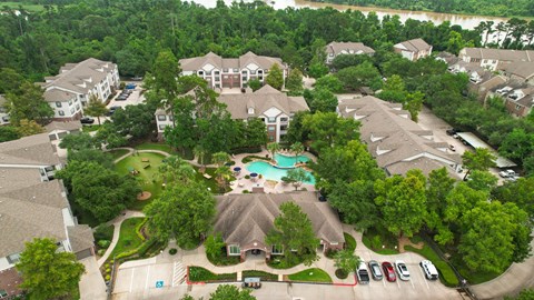 An aerial view of a residential complex with a swimming pool and surrounded by trees.