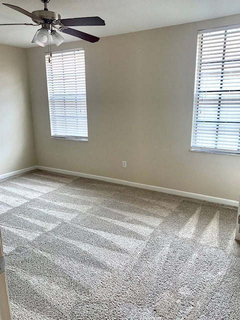 an empty room with a ceiling fan and two windows