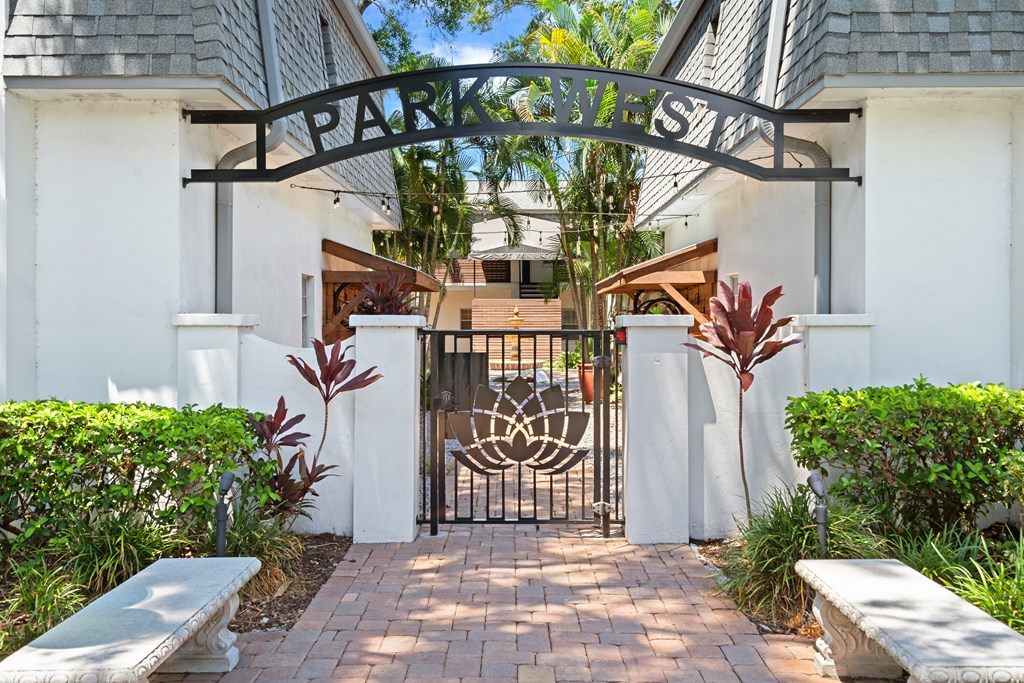 a wrought iron gate with a logo on it and two benches in front of it