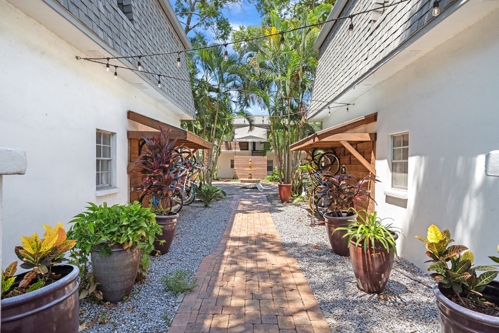 a courtyard with potted plants and a white building with a gray roof