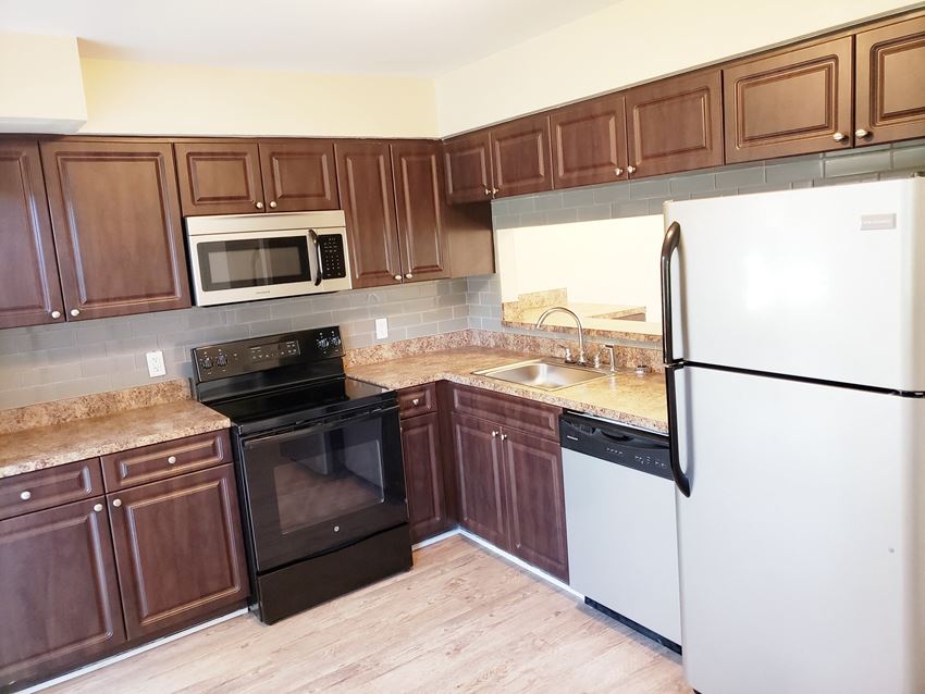 a kitchen with dark wood cabinets and white appliances - Photo Gallery