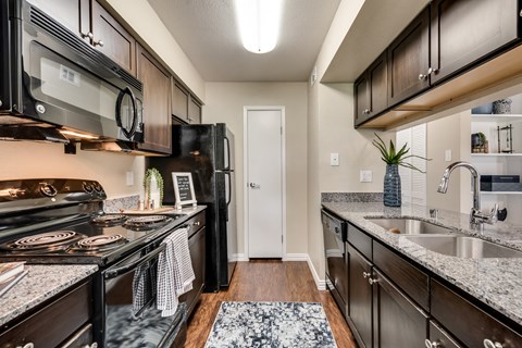 an updated kitchen with granite counter tops and black appliances