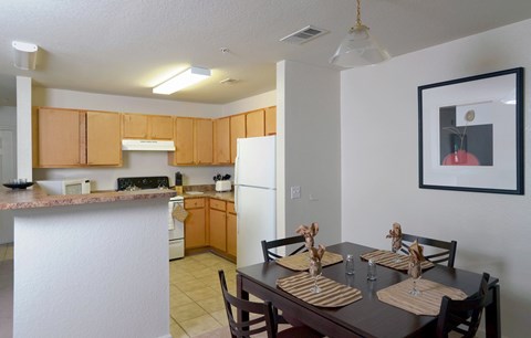 A kitchen with a table set for two with a white fridge in the background.