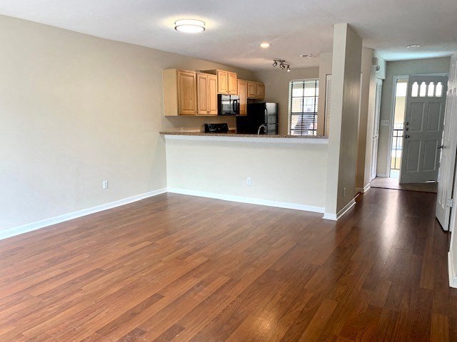 an empty living room with a kitchen in the background