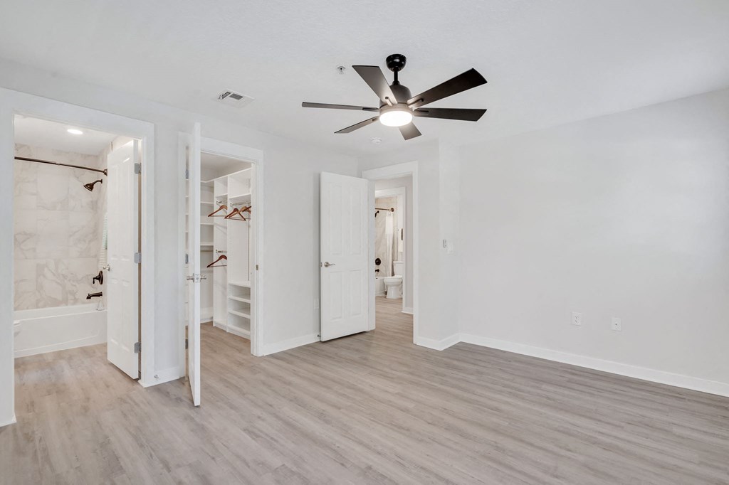 a bedroom with white walls and a ceiling fan