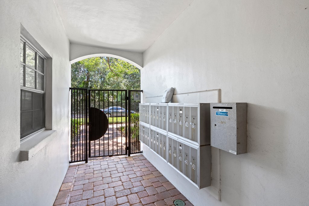 a gate opens to a driveway with a car in the distance